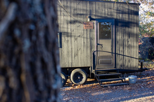 Dark wooden trailer with stairs and door.