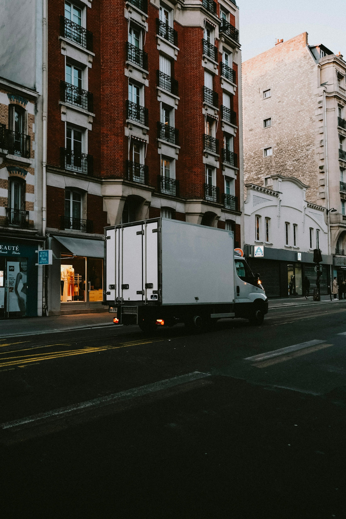 a delivery truck driving down a street next to tall buildings