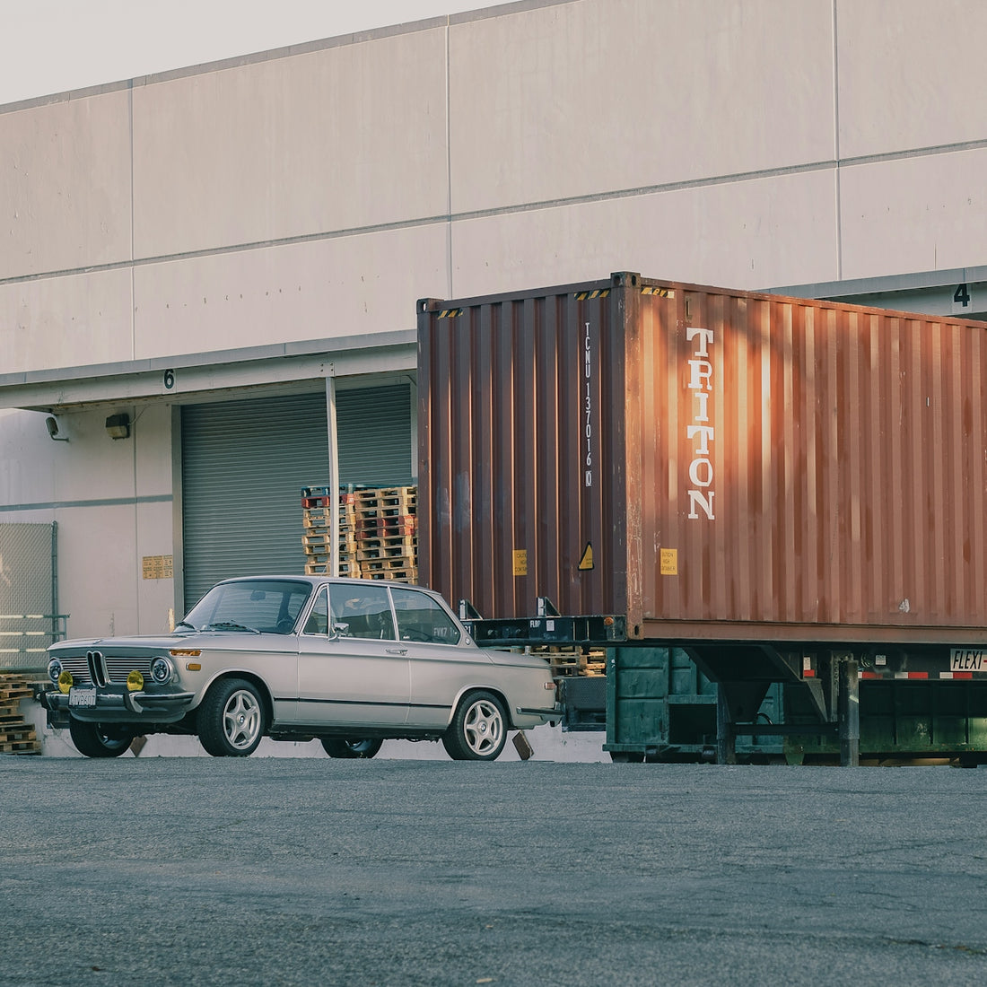 a car is parked in front of a shipping truck