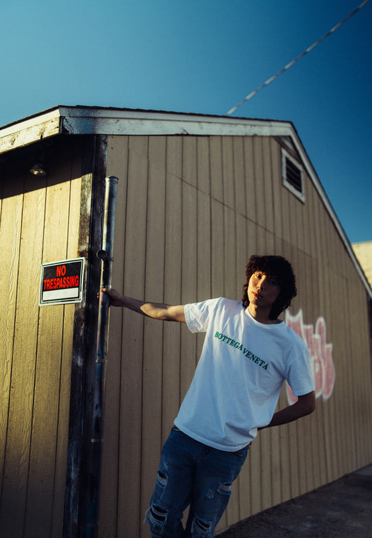 a young man leaning on a pole outside a building