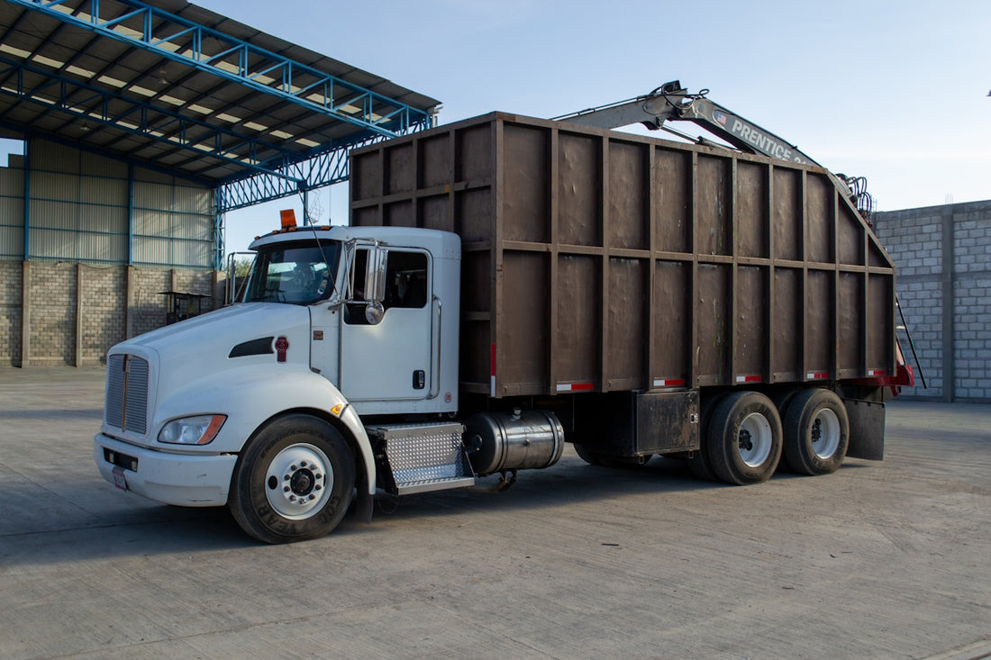 A white truck with a large brown container is parked.