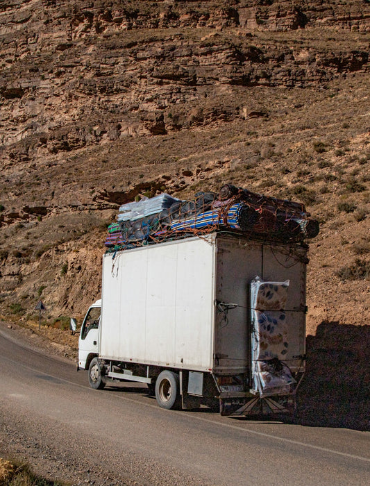 White truck overloaded with mattresses on a road.