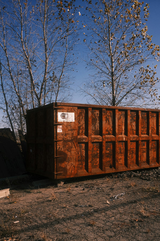 Rusty industrial dumpster in an outdoor lot.