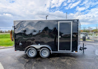 Front street-side view of 2026 Cargo Mate 7x14 tandem enclosed cargo trailer in black showing 18 inch V-nose, Cargo Mate branding, diamond plate stoneguard, and aluminum tread plate lower trim