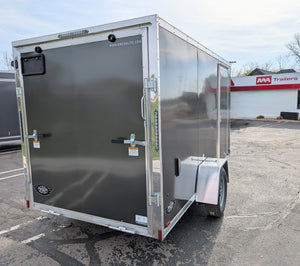 A 2025 Amerilite 6x12 Aluminum Enclosed Trailer with Ramp Door, displayed in a commercial setting with other vehicles in the background.