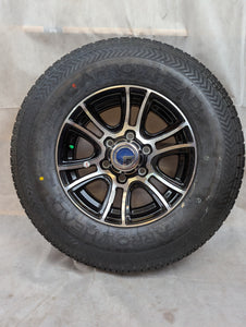 A 15 inch aluminum trailer wheel with a black and silver finish, mounted with a radial tire.