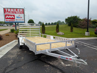 Silver Ox Aluminum  trailer with a wooden platform in front of a 'AAA Trailer Sales & Parts' sign.