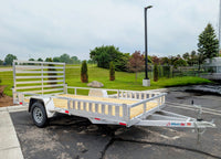 Silver Ox Aluminum utility trailer with a wooden bed parked on a paved surface with grass and trees in the background.