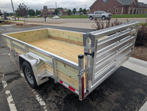 Silver Ox Aluminum  utility trailer parked in a parking lot with buildings and cars in the background.