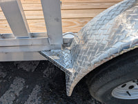 Close-up of a diamond plate fender on a trailer wheel with wooden background
