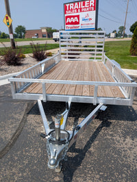 Silver Ox Trailer with wooden platform on a paved surface, with a 'AAA Trailer Sales & Parts' sign in the background.