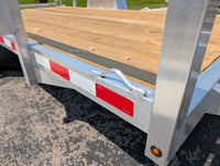 Wooden flatbed trailer with Aluminum frame and red and white safety stripes on a paved surface.