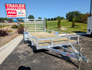 Silver Ox Utility trailer with wooden floor in a parking lot with 'Trailer Sales & Parts' sign in the background.