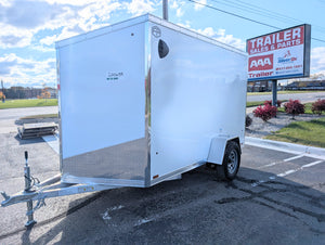 White 6x10 enclosed aluminum trailer parked in a lot with a AAA Trailer sign in the background.