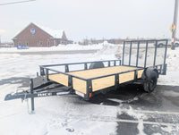 Rice utility trailer parked on a snowy street with a building and snowbank in the background.