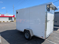 2026 AmeraLite Storm 6x10 White — curbside rear quarter view showing rear spoiler with loading lights, ramp door and man door | AAA Trailer