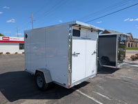 2026 AmeraLite Storm 6x10 White — curbside exterior with ramp door hardware and LED lighting strip detail