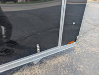 2026 AmeraLite Storm 6x10 Black — lower rear detail showing poly composite panel seam, extruded aluminum corner trim and cam latch hardware