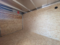 2026 AmeraLite Storm 6x10 interior — 3/4" OSB walls and floor, ramp door open, aluminum roof bows, loading light switch on wall
