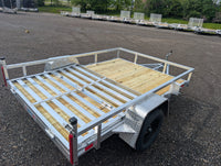 Silver Ox 7x10 Aluminum Utility Trailer with Folding Ramp Gate — aerial angle showing full deck, bi-fold gate fully deployed and aluminum extrusion frame | AAA Trailer