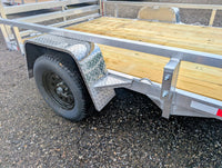 Silver Ox 7x10 Trailer — axle and wheel assembly closeup showing black mod wheel, EZ-Lube bearing cap and aluminum diamond plate fender skirt